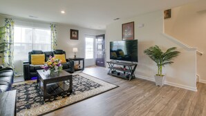 A living room with a sofa, coffee table, TV, and a staircase. - 9 Mi to Duke University: Spacious Home w/ Yard! (Durham)