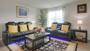A living room with a black leather sofa set, a wooden coffee table, a patterned rug, and a side table with a lamp. - 9 Mi to Duke University: Spacious Home w/ Yard! (Durham)