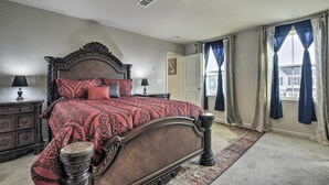 A bedroom with a large bed, a nightstand, a dresser, and a window with curtains. - 9 Mi to Duke University: Spacious Home w/ Yard! (Durham)