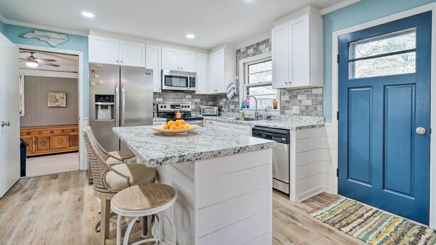 A modern kitchen with white cabinets, a blue door, and a granite countertop. - Cozy Wilmington Vacation Rental: 10 Mi to Beach! (Wilmington)