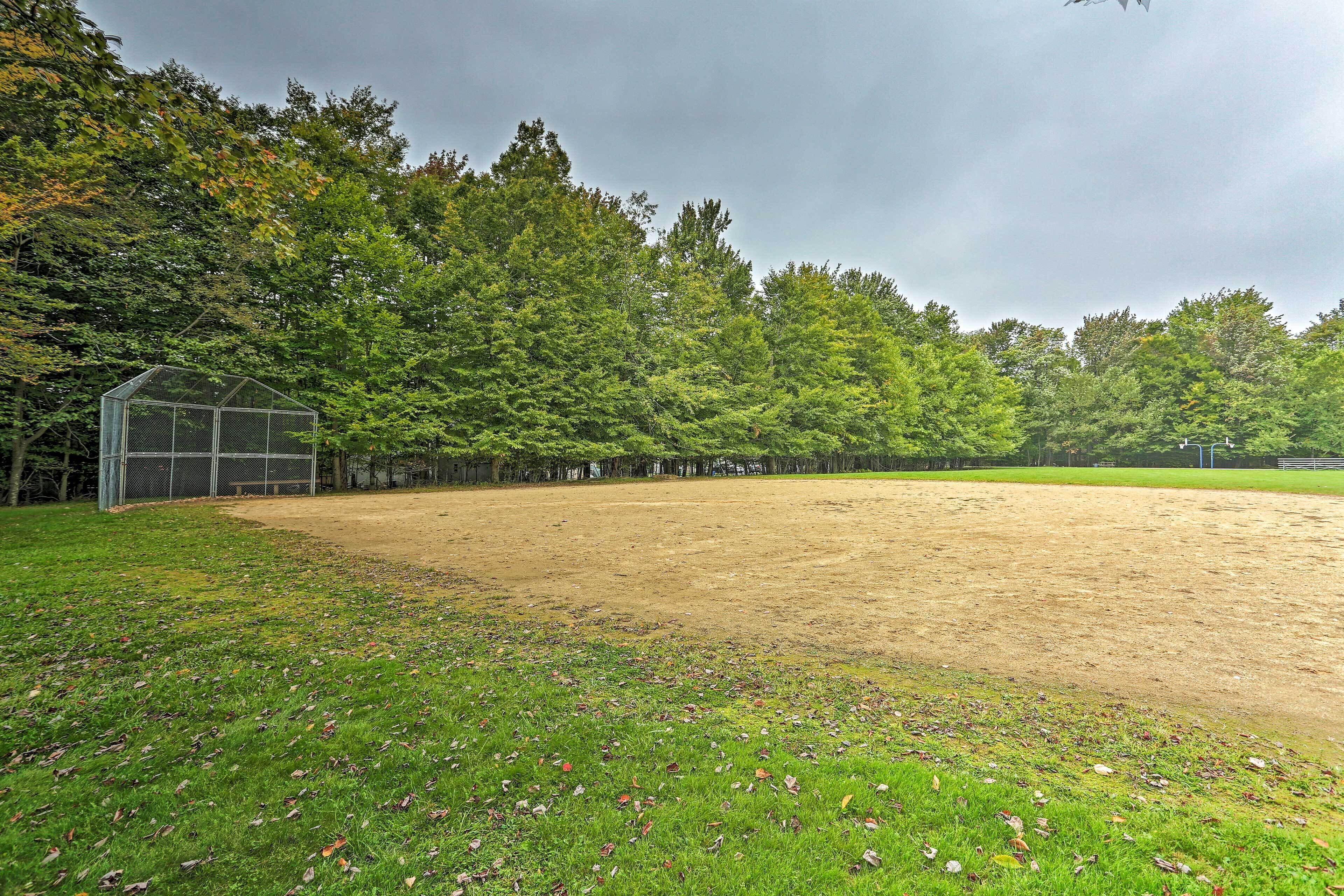 Ein Baseballfeld mit einer Gewächshauskonstruktion, umgeben von dichtem Baumbestand.