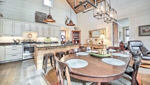 A spacious kitchen with wooden cabinets, a large island, and modern appliances. There is a dining area with a wooden table and chairs.
