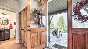 A wooden front door with a glass panel, a welcome mat, and a wreath.