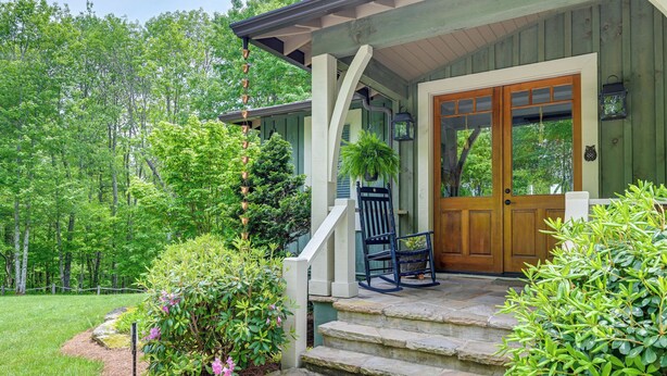A wooden house with a porch, stone steps, and a bench.