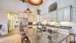 A spacious kitchen with a large island, stainless steel appliances, and pendant lighting.