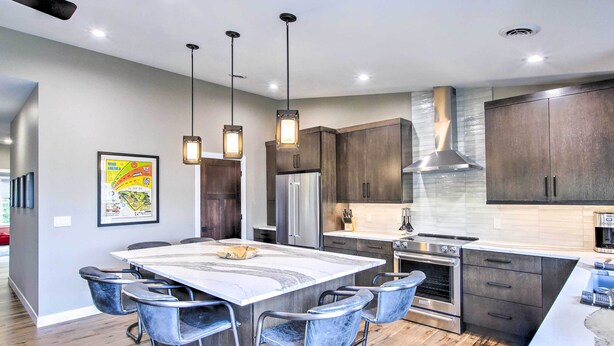 A modern kitchen with a marble island, dark wood cabinets, stainless steel appliances, and pendant lighting. - Chic Plymouth Townhome < 1 Mi to Road America (Plymouth)