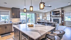 A modern kitchen with a large island, pendant lighting, and a stone fireplace. - Chic Plymouth Townhome < 1 Mi to Road America (Plymouth)