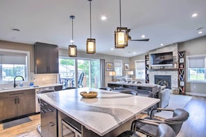 A modern kitchen with a large island, pendant lighting, and a stone fireplace. - Chic Plymouth Townhome < 1 Mi to Road America (Plymouth)