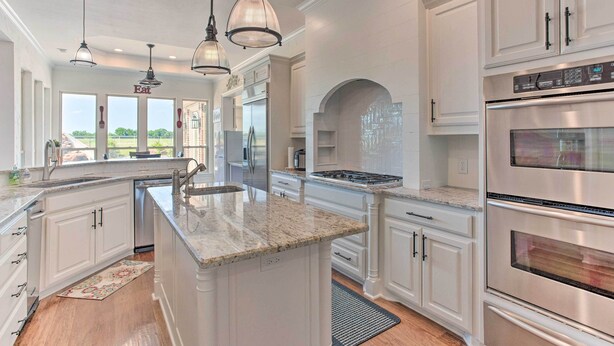 A spacious kitchen with white cabinetry, a large island, stainless steel appliances, and pendant lighting. - Chic Ranch Villa < 5 Mi to Lake Ray Roberts! (Pilot Point)