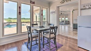 A dining area with a view of a swimming pool, a kitchen with a refrigerator, and a living area with a fireplace. - Chic Ranch Villa < 5 Mi to Lake Ray Roberts! (Pilot Point)