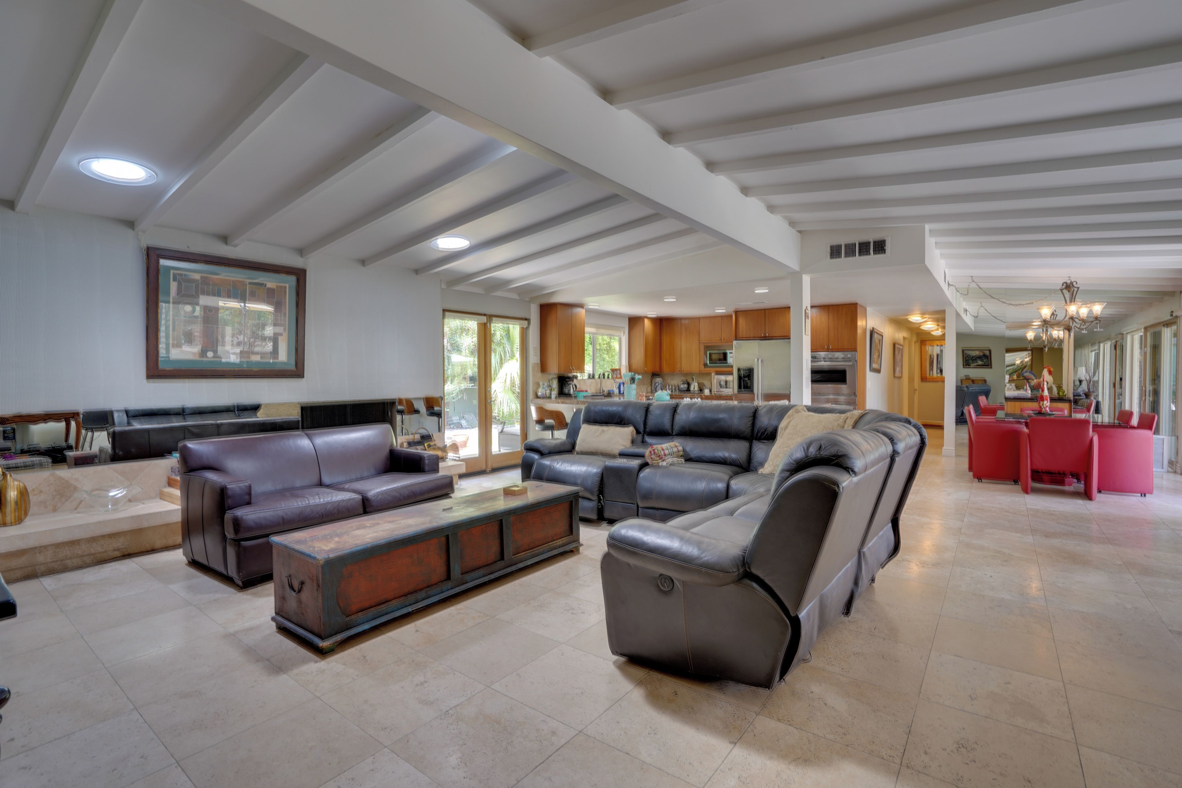 Ein geräumiges Wohnzimmer mit Ledersofas, einem Holztisch und einer Küche im Hintergrund.