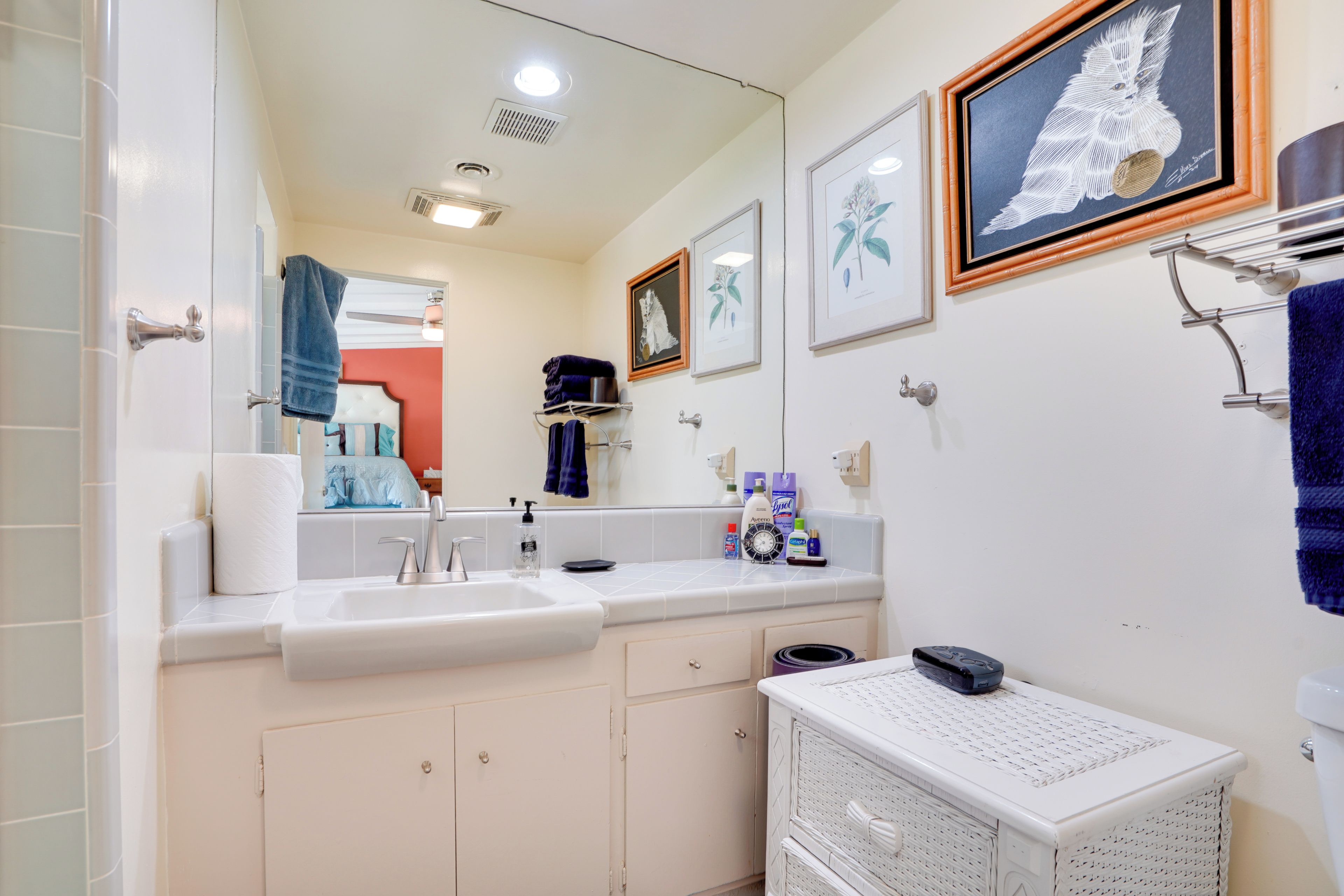 Un baño con un lavamanos blanco, un espejo y una obra de arte enmarcada en la pared.
