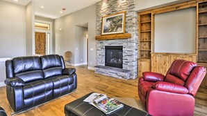 A living room with a stone fireplace, leather sofas, and a wooden cabinet.