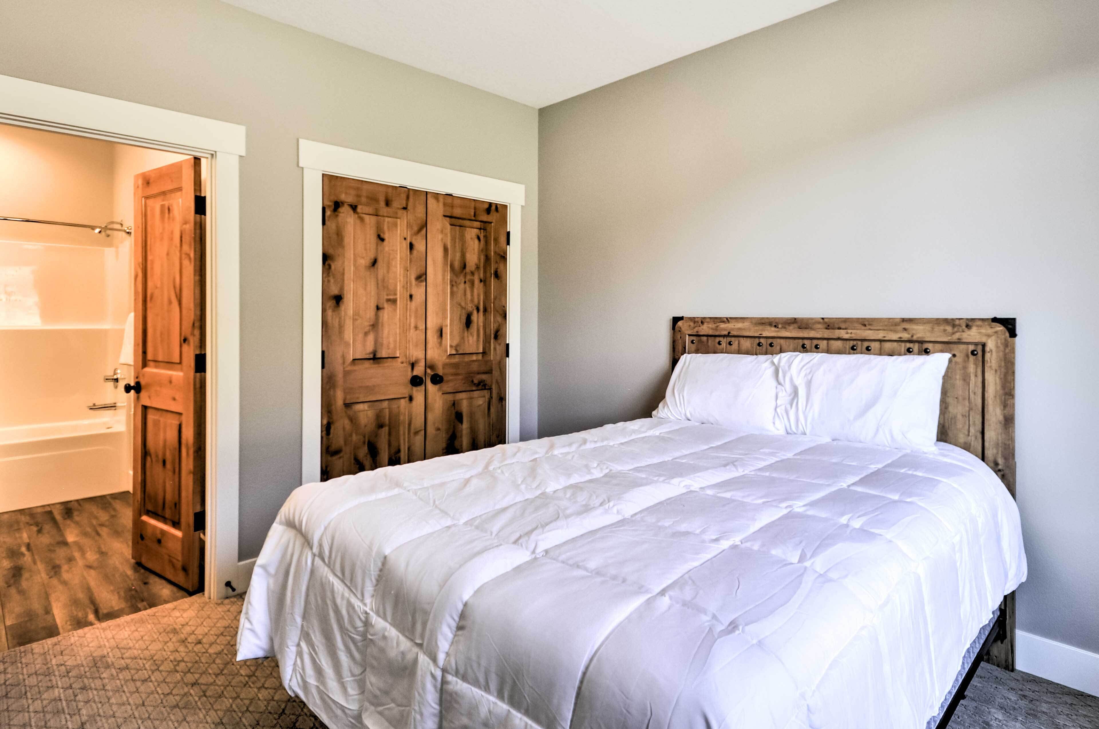 Une chambre avec un grand lit, une armoire en bois et une salle de bain avec une baignoire.