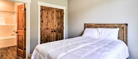 Une chambre avec un grand lit, une armoire en bois et une salle de bain avec une baignoire.