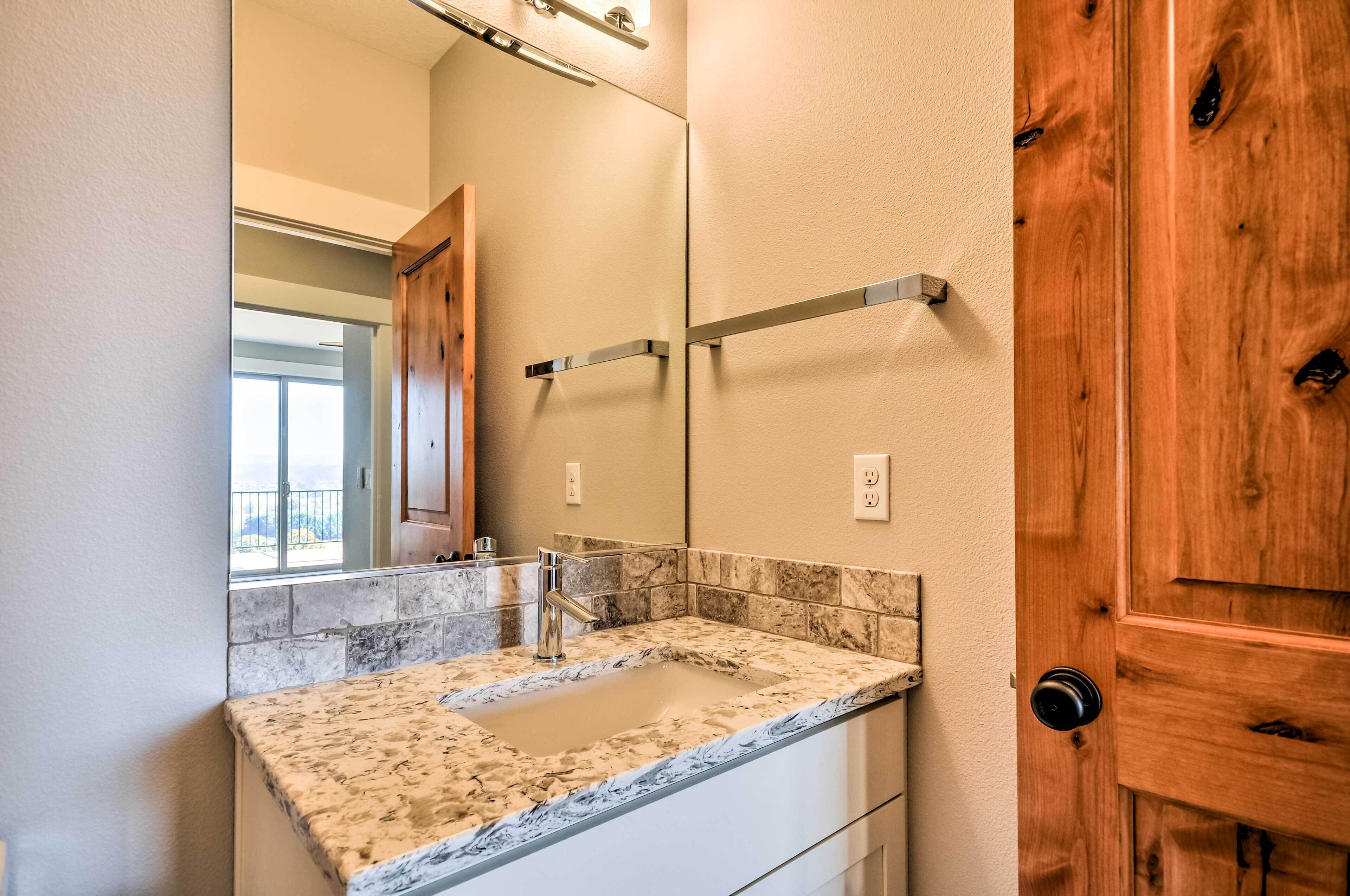 Une salle de bain avec un lavabo en marbre, une porte en bois et un miroir au-dessus du lavabo.