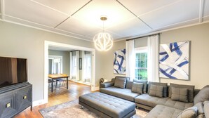 A modern living room with a sectional sofa, ottoman, dark wooden cabinet, and abstract art on the walls. - Chester Home ~ 12 Mi to Magic Mountain Ski Area (Chester)