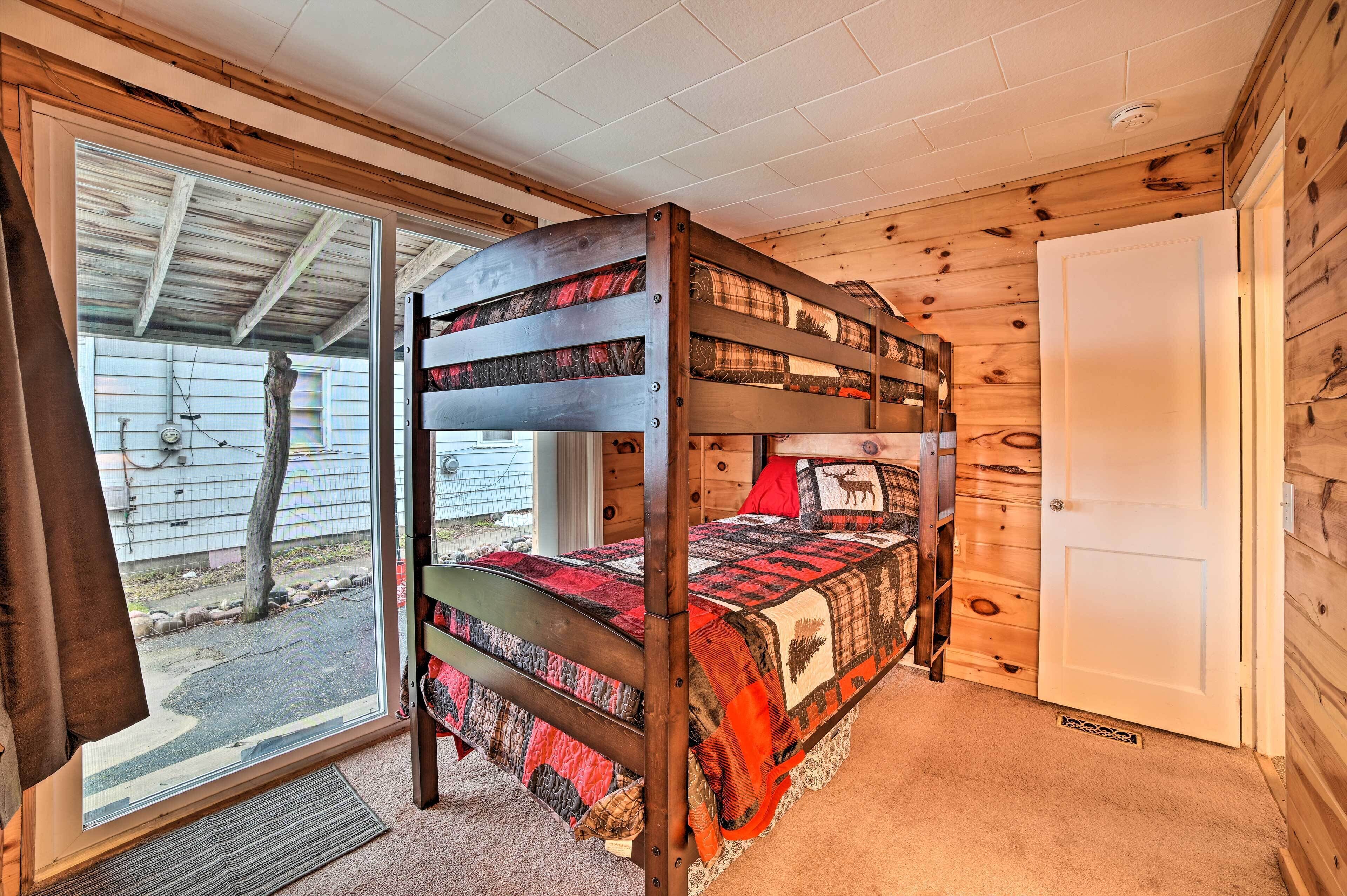 A bunk bed with a plaid bedspread and a wooden headboard.