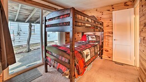A bunk bed with a plaid bedspread and a wooden headboard.