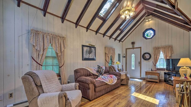 Una habitación acogedora con pisos de madera, un sofá marrón, un sillón cómodo y una mesa de centro de madera.