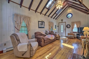 A cozy room with wooden floors, a brown sofa, a cushioned armchair, and a wooden coffee table. - Dog-friendly Waretown Home w/ Furnished Deck! (Waretown)