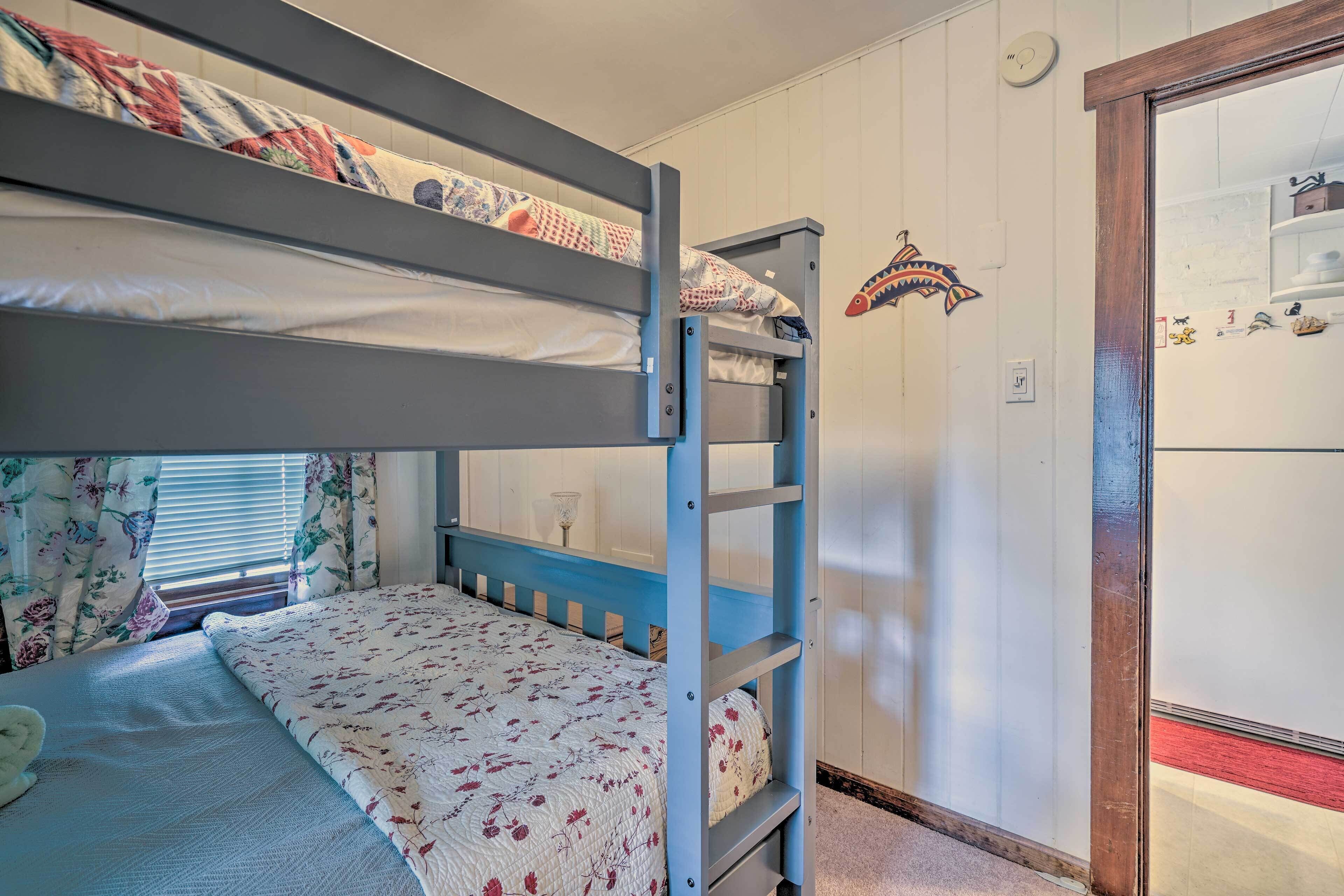 A bunk bed room with a ladder, floral bedding, and a fish decoration on the wall.