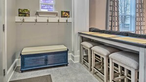 A kitchen with a built-in bench, bar stools, a window with blinds, and decorative wall art. - Charming Greencastle Home < 1 Mi to Depauw! (Greencastle)