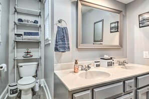 A modern bathroom with a white toilet, a double sink vanity, a large mirror, and a towel rack.