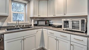 A modern kitchen with white cabinets, a built-in microwave, a toaster oven, and a window with a view of trees. - Charming Greencastle Home < 1 Mi to Depauw! (Greencastle)
