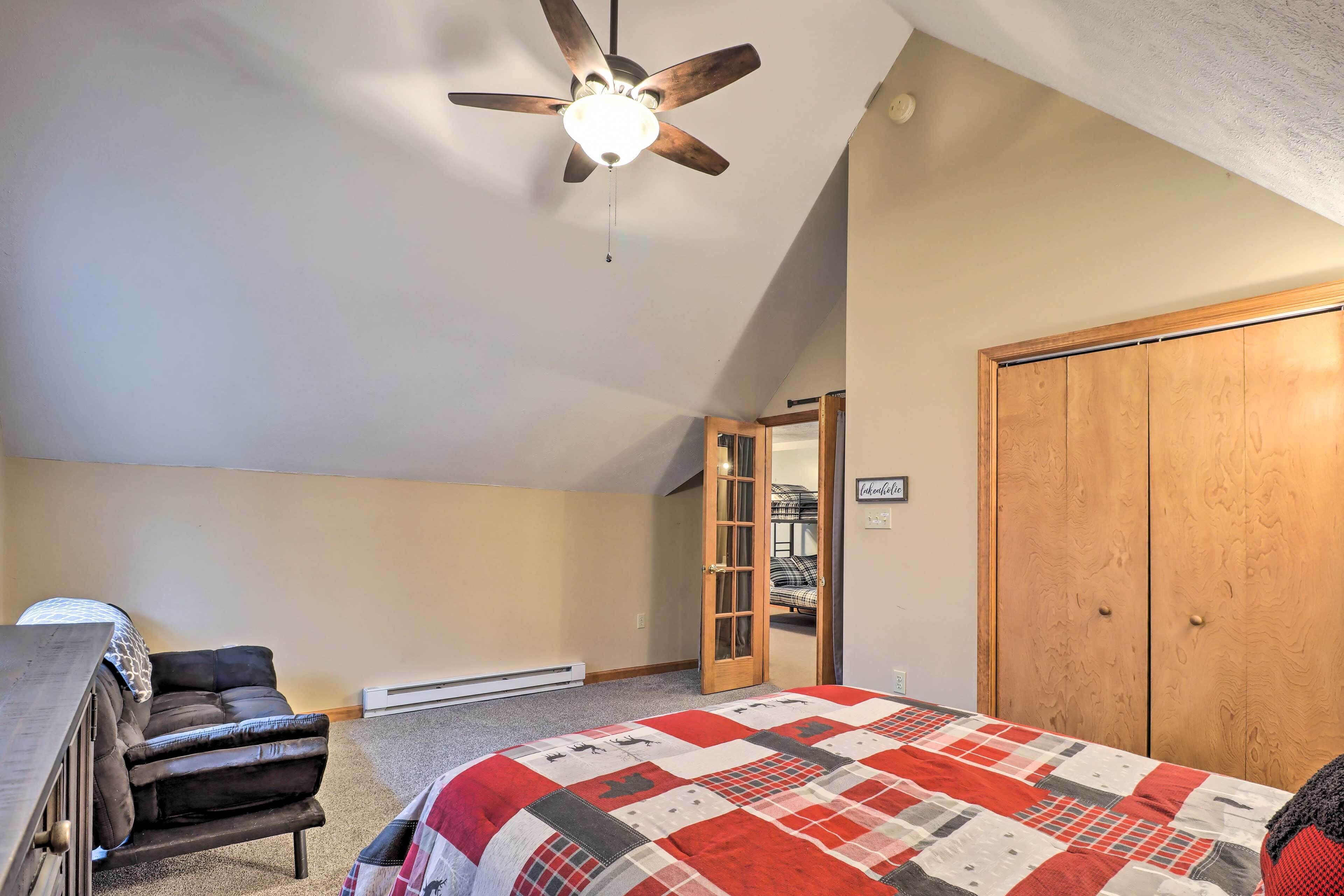A bedroom with a bed, a desk, a chair, a ceiling fan, and a wardrobe.