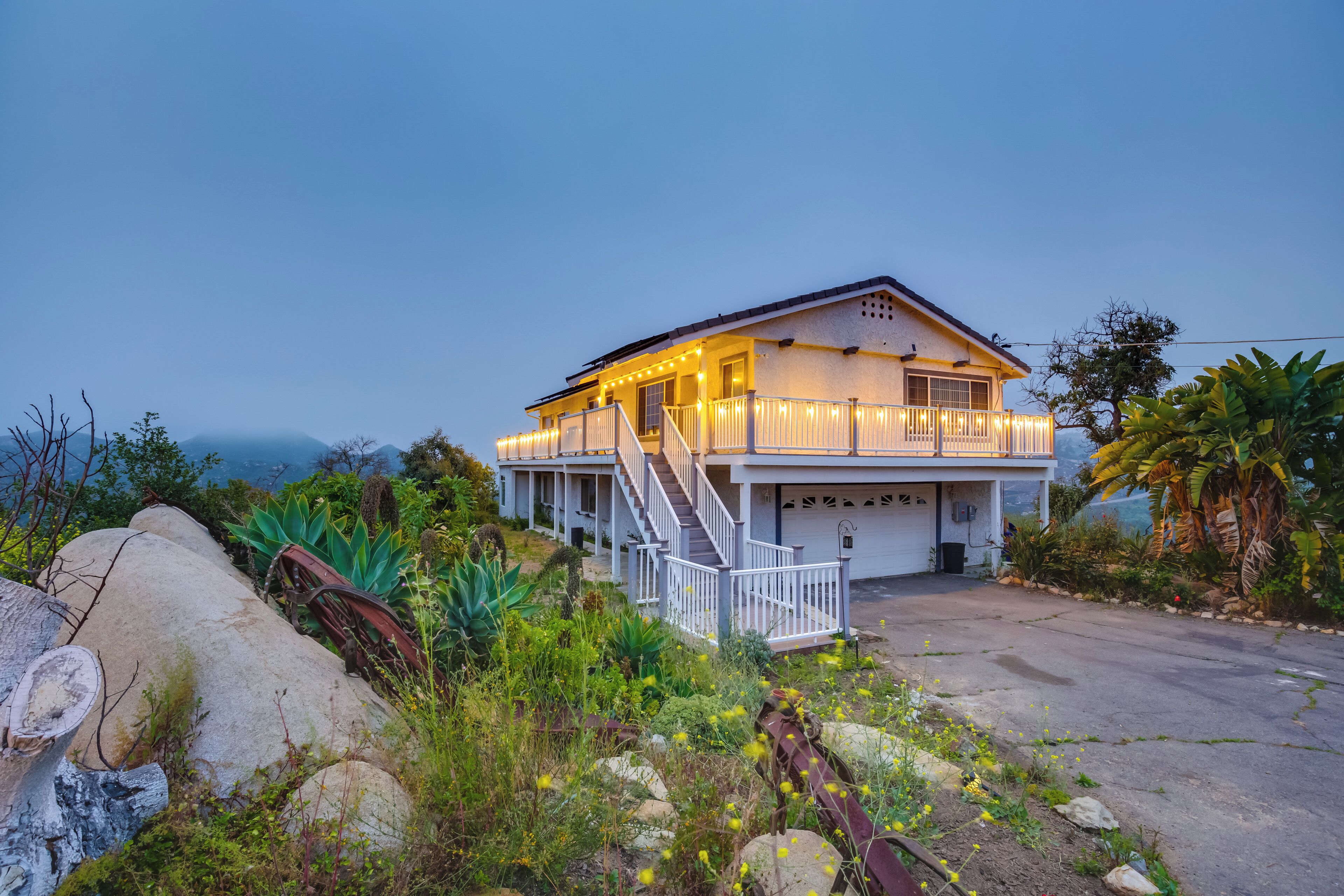Ein zweistöckiges Haus mit überdachter Veranda, einer Treppe und einer Garage.