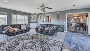 A modern living room with two sofas, a coffee table, and a ceiling fan.