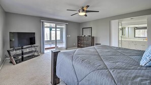 A bedroom with a bed, a ceiling fan, a TV on a stand, and a dresser.
