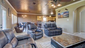 A spacious living area with leather sofas and a marble coffee table, a kitchen with pendant lights, and a dining area with bar stools.