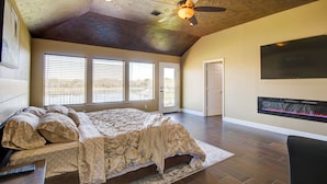 A spacious bedroom with a large bed, a ceiling fan, and a fireplace.