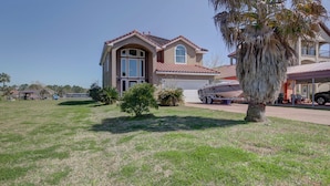 A two-story house with a garage, a boat on a trailer, and a palm tree in the front yard.