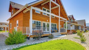 Ein zweistöckiges Holzhaus mit verdeckter Veranda, großen Fenstern und einem gepflegten Rasen.