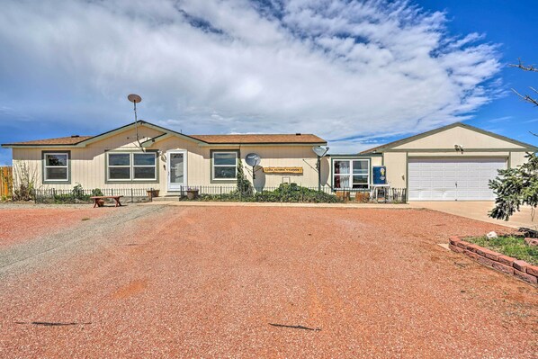 A two-story house with a garage, a satellite dish, and a well-maintained gravel driveway.