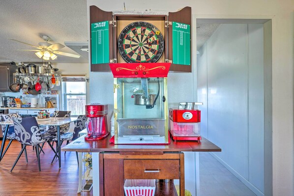A dartboard mounted above a Nostalgia ice cream maker, with a kitchen in the background.