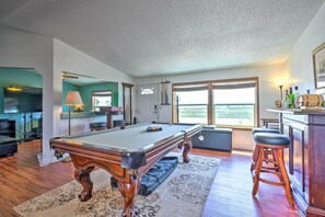A pool table in a room with a large window, a bar area, and a television.