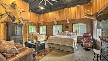 A spacious room with a large bed, a leather sofa, and a massage chair.