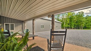 An outdoor patio area with a covered seating area, a gravel driveway, and a house in the background. - Family Leatherwood Resort Cabin w/ Fire Pit! (Dover)