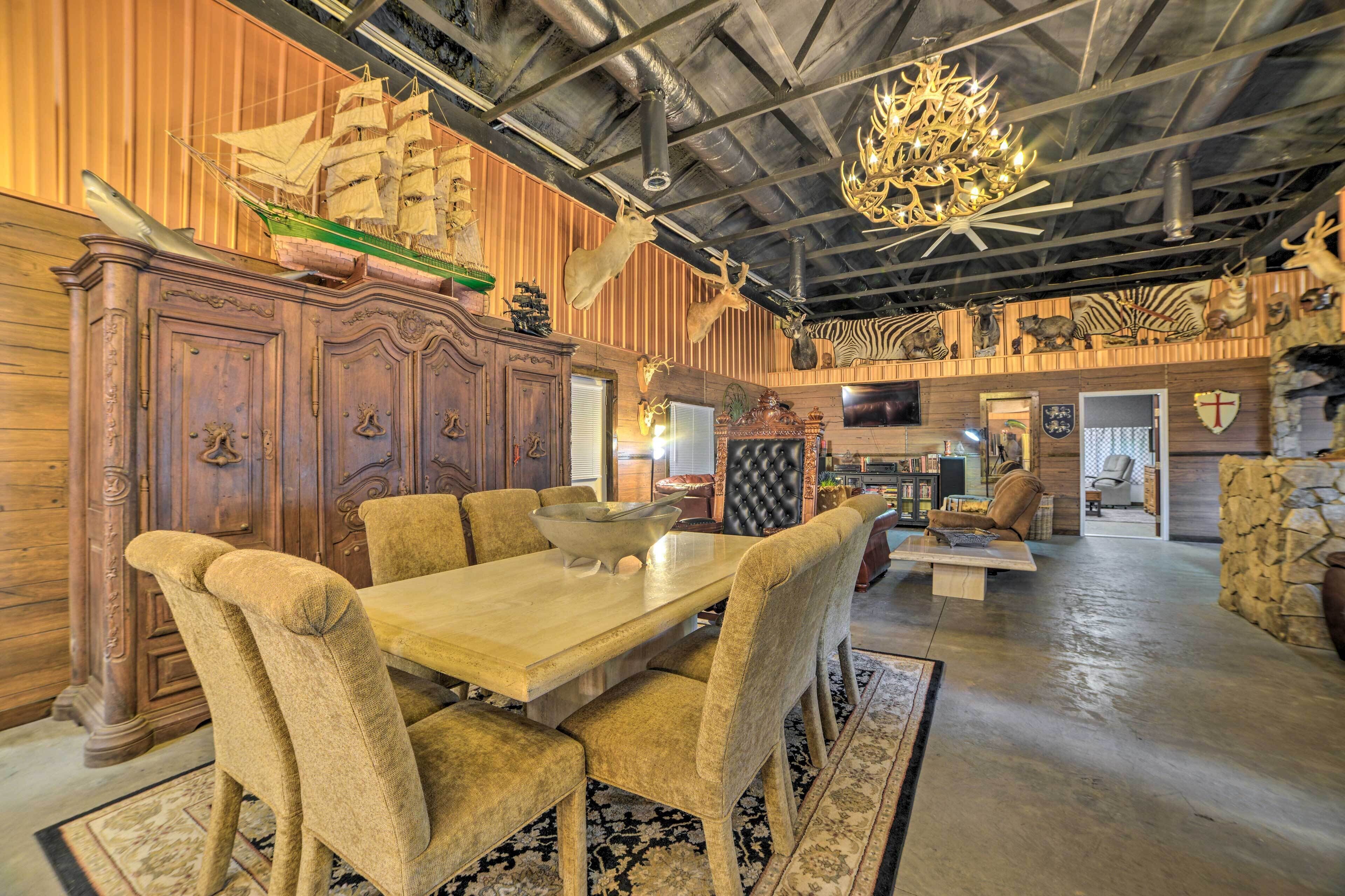 A dining area with a wooden table and upholstered chairs, a chandelier, and a ship model on the wall.