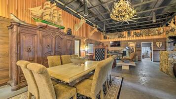 A dining area with a wooden table and upholstered chairs, a chandelier, and a ship model on the wall.