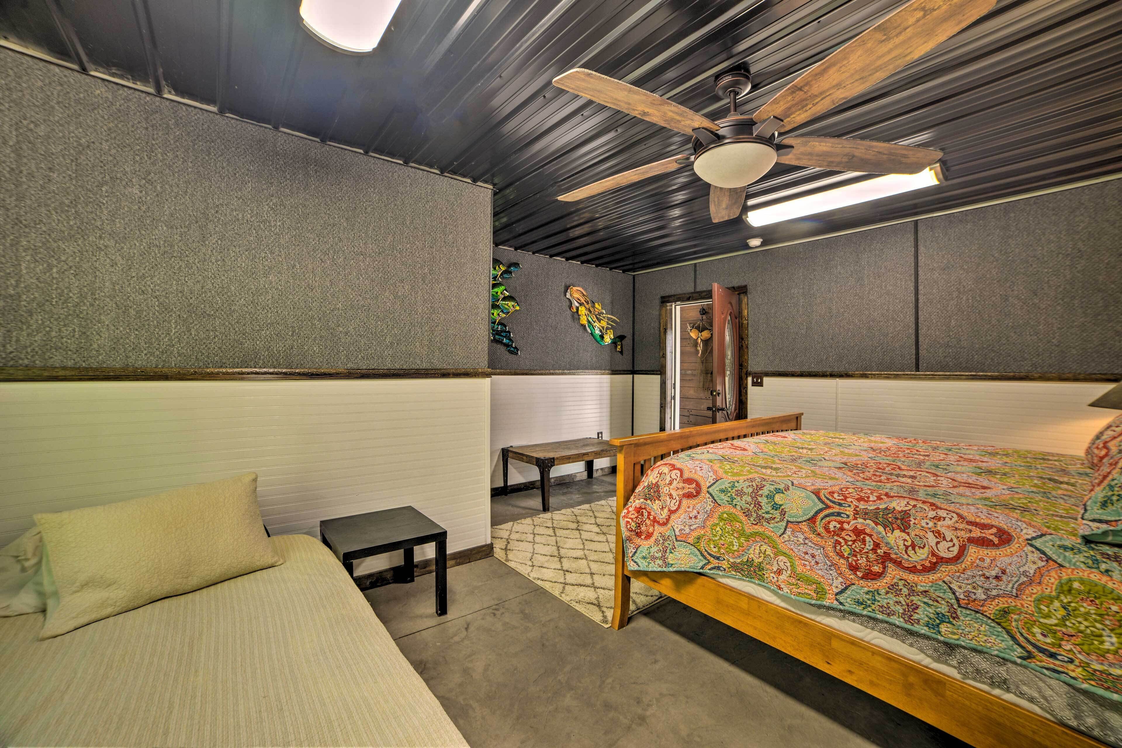 Une chambre à coucher avec un lit, une petite table, un ventilateur de plafond et une porte.