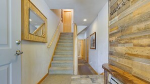 A hallway with a wooden staircase, a wooden bench, and a wall with a wooden panel design. - Downtown Winter Park Townhouse 3 Mi to Ski Resort! (Winter Park)