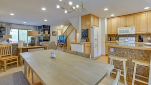 A spacious kitchen with wooden cabinets, a dining area with a large table, and a staircase leading to an upper level. - Downtown Winter Park Townhouse 3 Mi to Ski Resort! (Winter Park)
