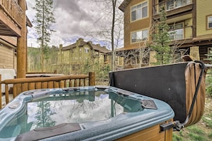 A hot tub in a backyard with wooden deck and a view of a multi-story building. - Downtown Winter Park Townhouse 3 Mi to Ski Resort! (Winter Park)