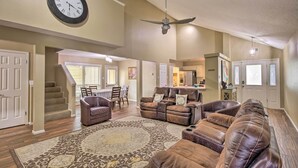 A spacious living room with a large brown leather sofa, a brown leather recliner, and a patterned rug. There is a ceiling fan, a clock, and a dining area in the background. - Family Retreat ~ 1 Mi to Hill Country Mile! (Boerne)