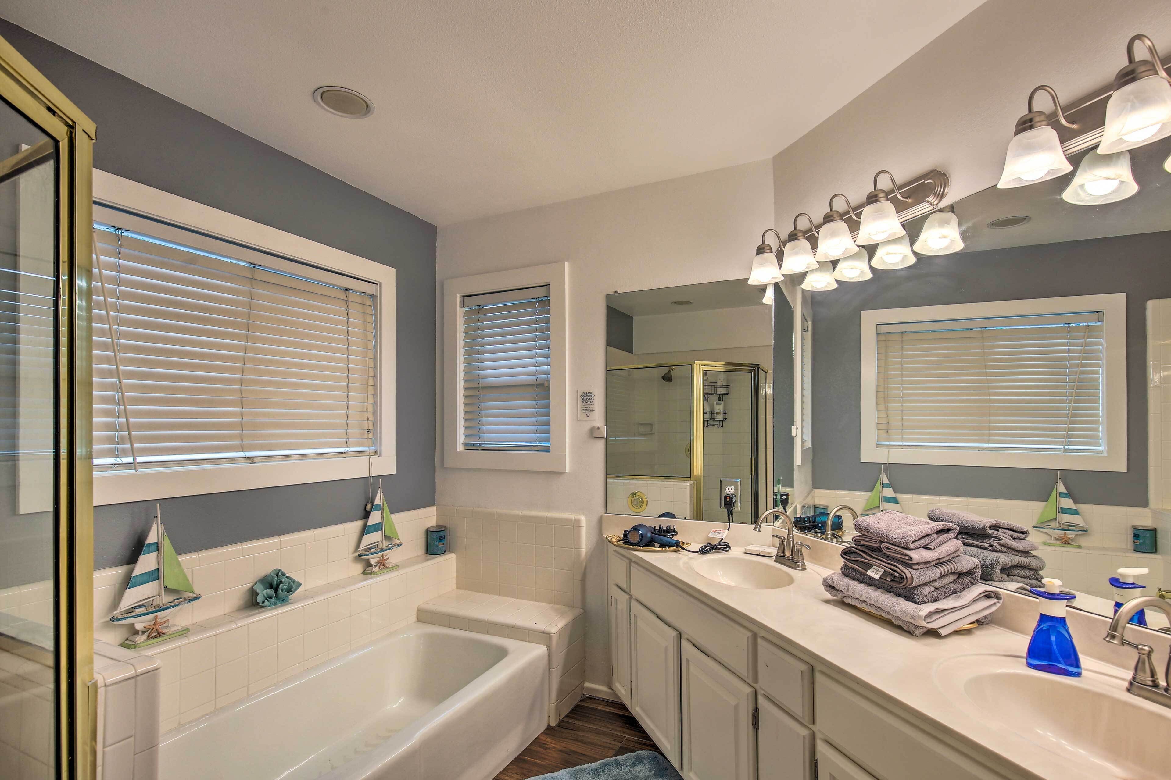 A bathroom with a bathtub, two sinks, and a large mirror.